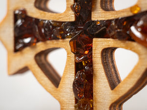 Macro close-up of BalticBliss genuine amber cross showing rich cognac Baltic amber chips set in layered birch wood, authentic Lithuanian handmade religious dΓ©cor detail, real Baltic amber art for spiritual home gifts.