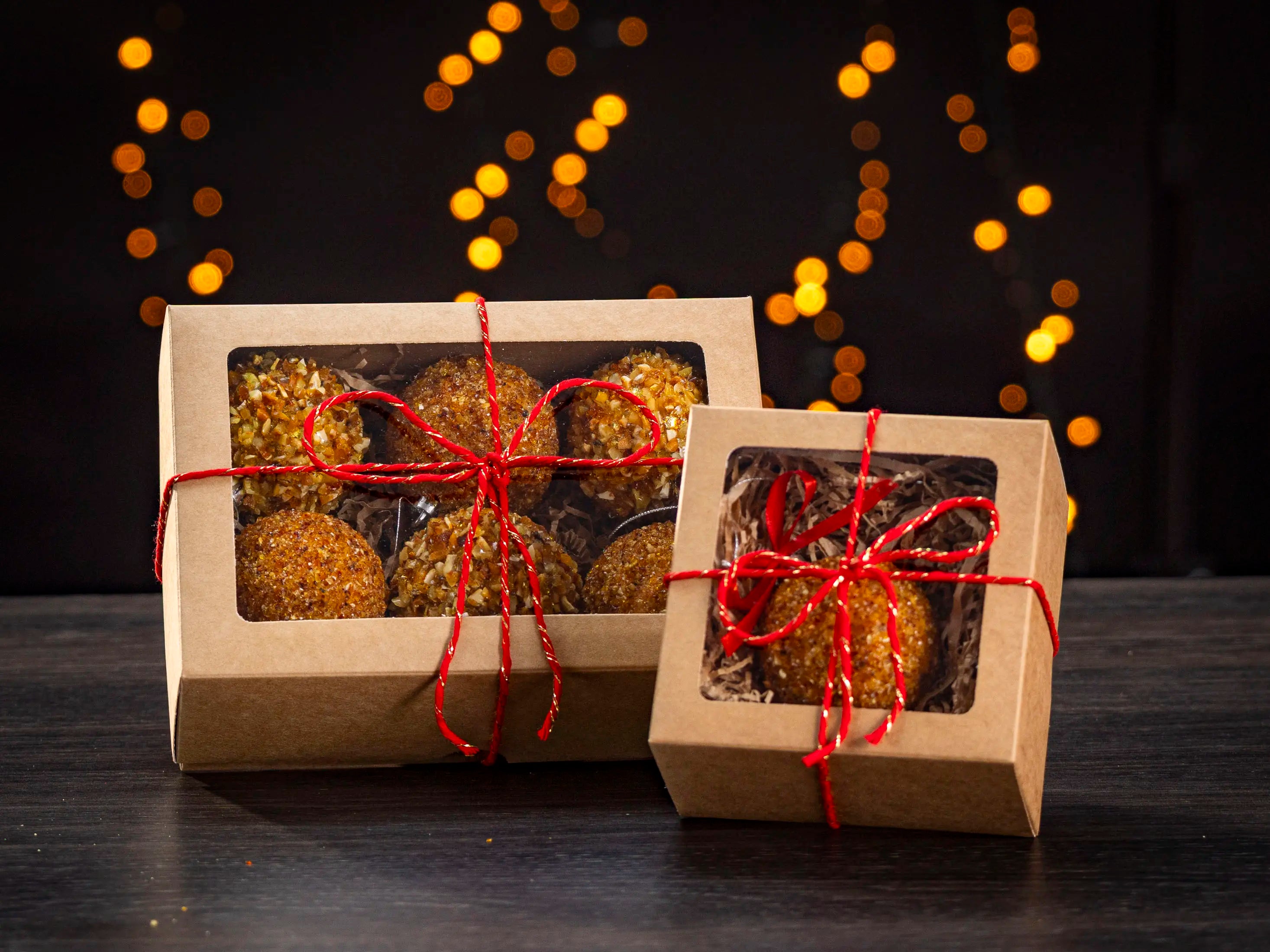 BalticBliss genuine Baltic amber Christmas ornament balls gift set in eco‑friendly kraft window boxes—six‑piece and single‑piece packaging options tied with red string—handmade in Lithuania, authentic Baltic amber holiday décor ships worldwide