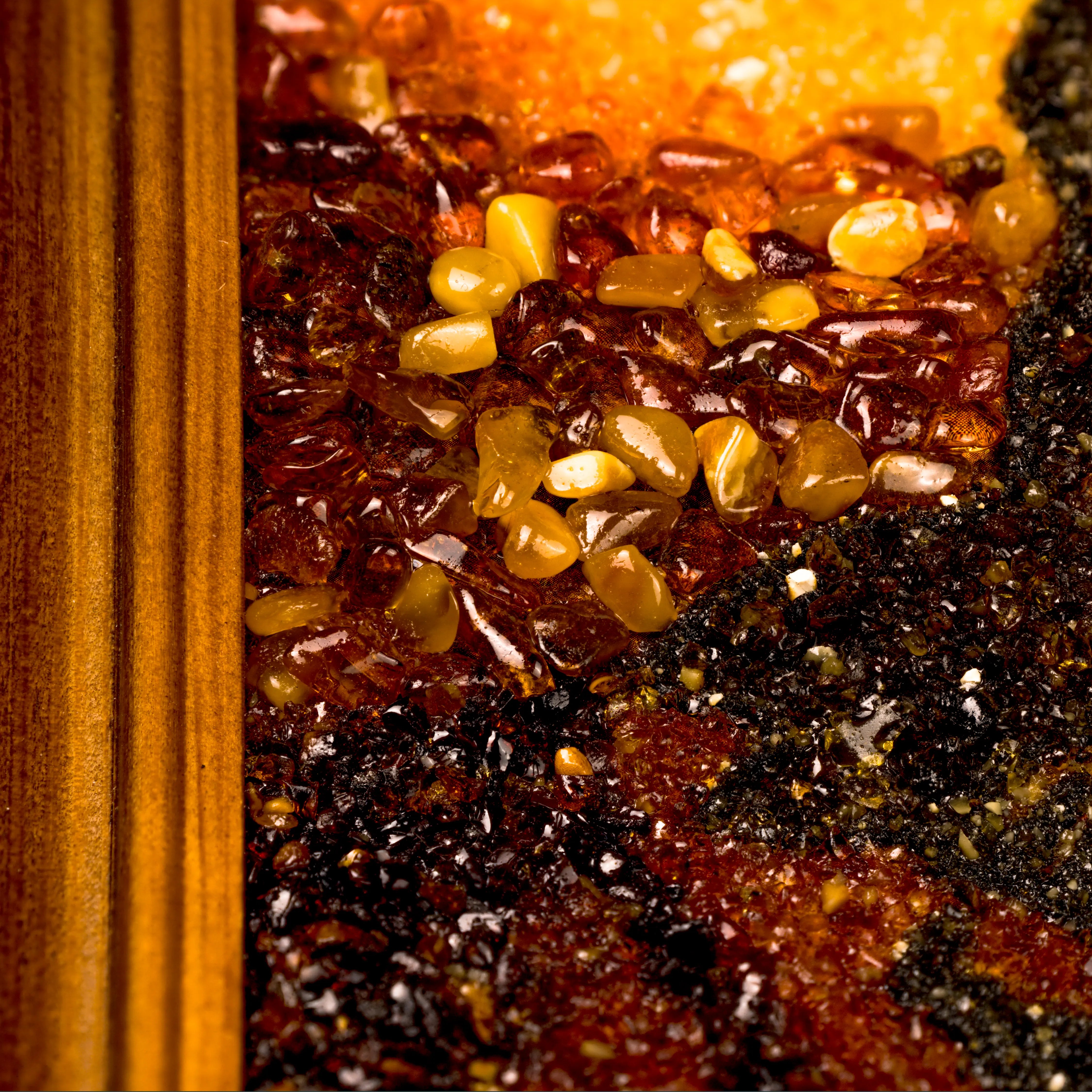 Extreme close-up of BalticBliss genuine amber artwork showing a cluster of natural polished Baltic amber stones and fine amber grain texture, highlighting premium Lithuanian handmade amber craftsmanship and exquisite detail.